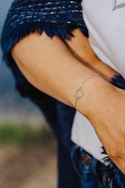 Christian model wearing gold vermeil crown of thorns bracelet with cross tag by Rizen Jewelry