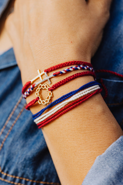 Christian model wearing faith inspired friendship bracelet with gold crown of thorns pendant hand braided garnet red cords by Rizen Jewelry.  Layered with multiple Made 4 Ministries collection bracelets. 