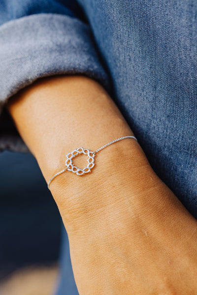 Christian model wearing sterling silver crown of thorns bracelet with cross tag by Rizen Jewelry. 