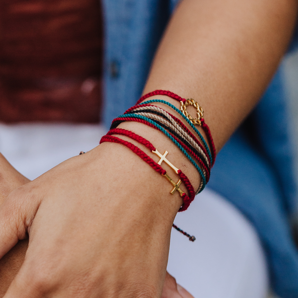 Rizen Jewelry faith model wearing Made4Ministry red gold crown of thorns bracelet with christian cross fmacrame friendship bracelets. 