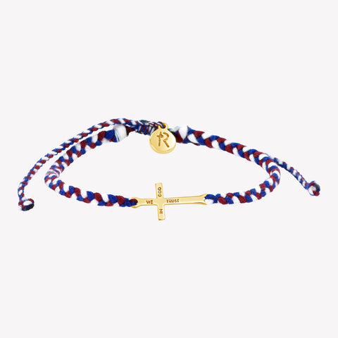 gold cross bracelet hand braided in red, white, blue cotton cord, engraved "WE TRUST IN GOD" with Rizen Jewelry and Made 4 Ministries round disc tag. 